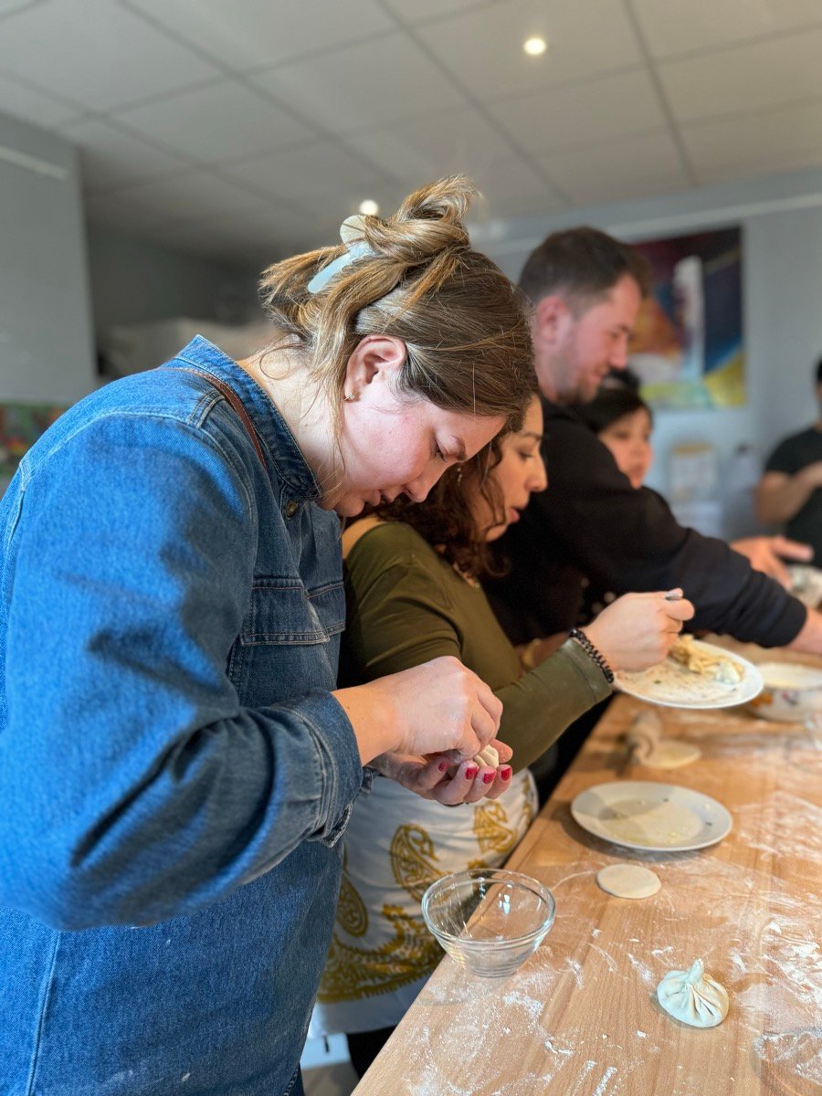 Mehrere Personen formen gemeinsam Teigtaschen an einem Holztisch